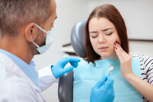 A woman is having her teeth examined by a dentist, emphasizing the need for care in dental emergency.